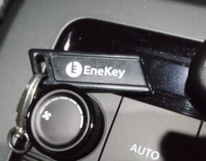 車内のダッシュボード付近に置かれたエネキーのクローズアップ。黒いエネキーと操作ノブが写る実写写真。